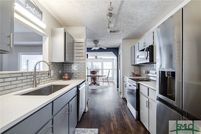 kitchen with dark wood-type flooring, stainless steel appliances, a textured ceiling, and decorative backsplash