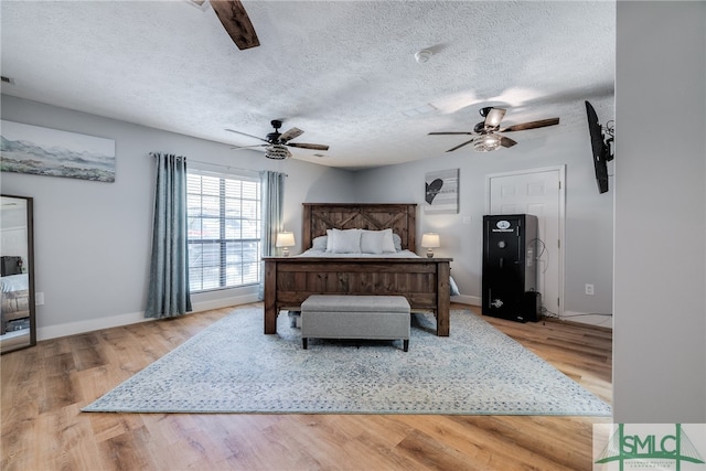 bedroom with light hardwood / wood-style flooring, a textured ceiling, and ceiling fan