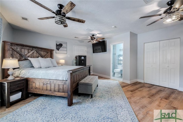 bedroom with a textured ceiling, ensuite bathroom, ceiling fan, and light hardwood / wood-style flooring