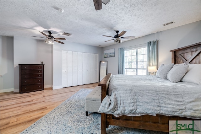 bedroom with ceiling fan, hardwood / wood-style flooring, and a textured ceiling