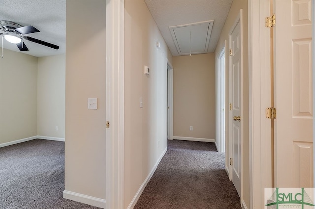 hall featuring a textured ceiling and dark carpet