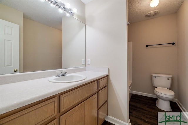 bathroom featuring vanity, a textured ceiling, hardwood / wood-style flooring, and toilet