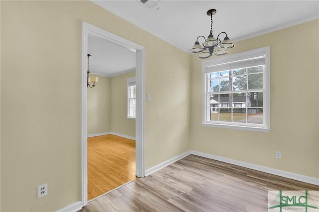 unfurnished dining area featuring a chandelier and light hardwood / wood-style floors