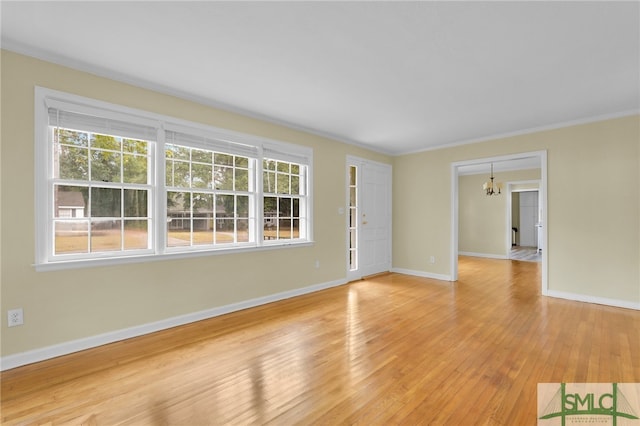 spare room featuring light hardwood / wood-style floors, an inviting chandelier, and ornamental molding