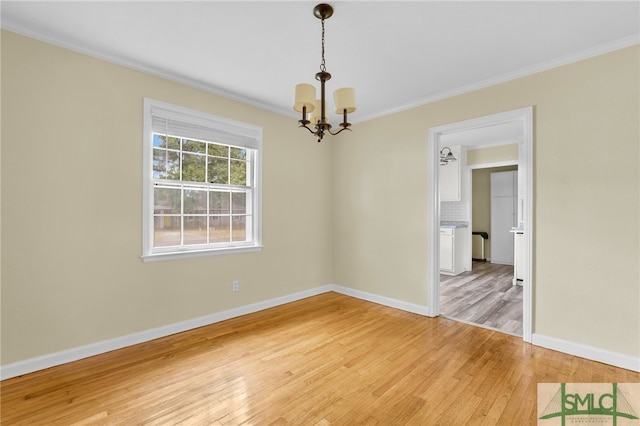 empty room with ornamental molding, light wood-type flooring, and a notable chandelier