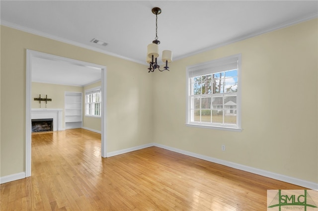 unfurnished dining area featuring a notable chandelier, ornamental molding, built in features, and wood-type flooring