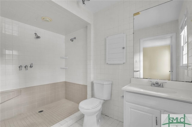 bathroom featuring tile patterned flooring, toilet, vanity, a shower, and tile walls