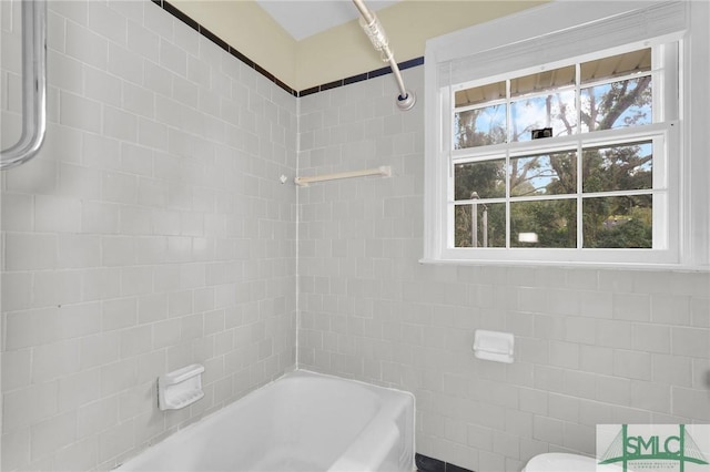 bathroom with toilet and tiled shower / bath