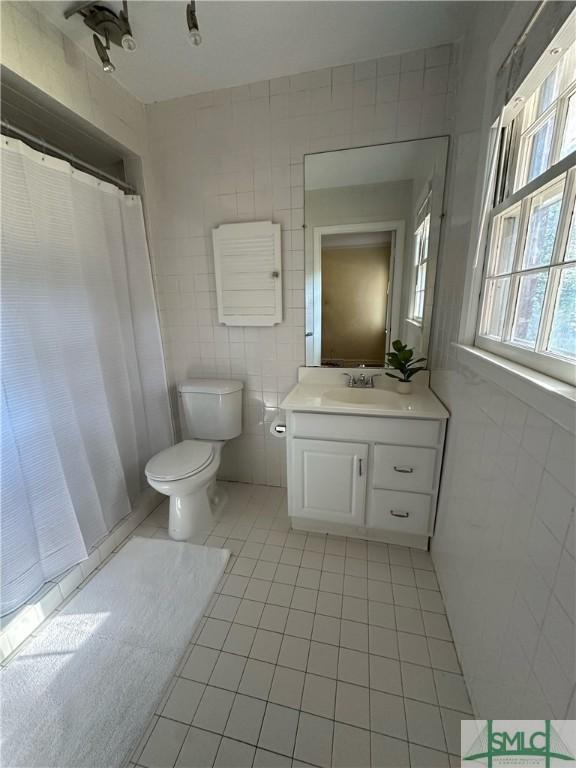 bathroom featuring tile walls, toilet, vanity, and tile patterned floors