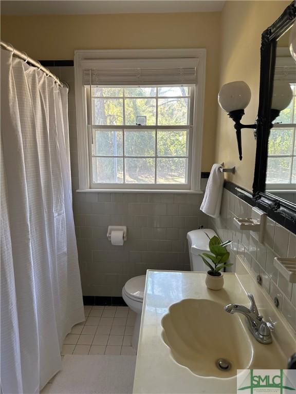 bathroom featuring toilet, tile patterned floors, a shower with curtain, tile walls, and sink