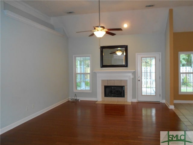 unfurnished living room with wood-type flooring, ceiling fan, vaulted ceiling, and a tile fireplace