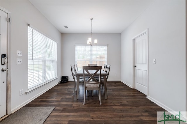 dining space with dark hardwood / wood-style flooring and an inviting chandelier