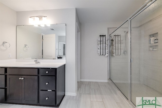 bathroom featuring a shower with door and vanity