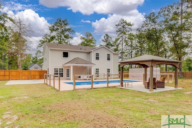 rear view of property featuring a fenced in pool, a patio area, a lawn, and a gazebo