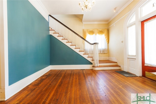 entryway with hardwood / wood-style floors, a notable chandelier, crown molding, and plenty of natural light