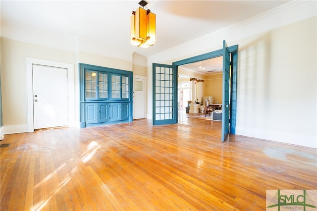 unfurnished living room featuring french doors, wood-type flooring, and crown molding