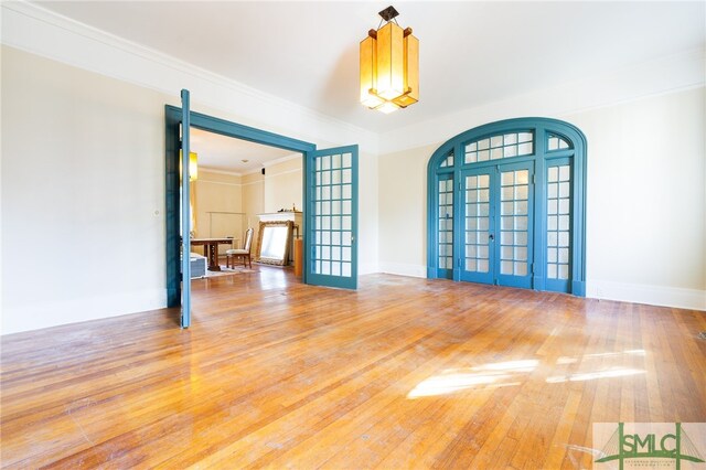 empty room with french doors, ornamental molding, and wood-type flooring