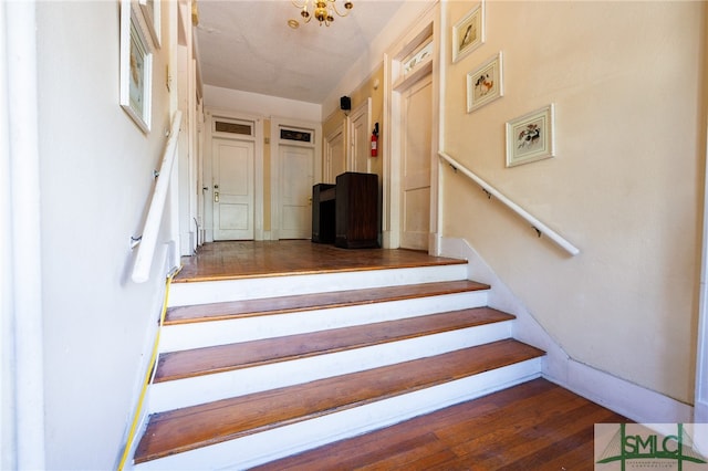 staircase with hardwood / wood-style flooring and an inviting chandelier