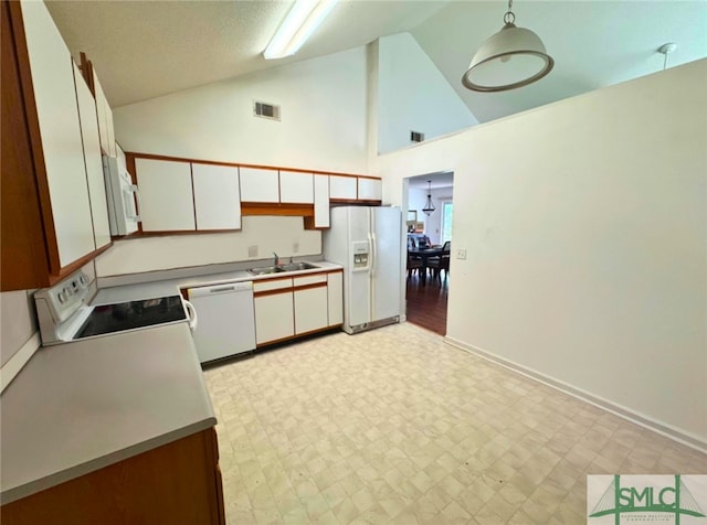 kitchen featuring white appliances, white cabinetry, a sink, light flooring, and high vaulted ceiling