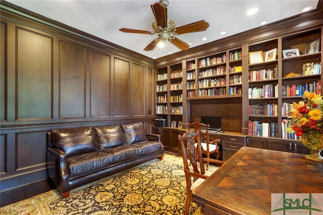 home office featuring built in desk, built in features, wood-type flooring, and ornamental molding