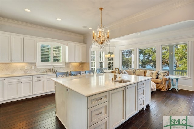 kitchen featuring pendant lighting, dark hardwood / wood-style flooring, sink, and an island with sink