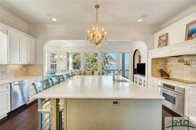 kitchen with stainless steel appliances, white cabinetry, sink, an island with sink, and a kitchen breakfast bar