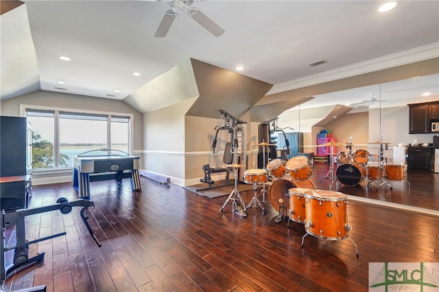 workout area featuring dark wood-type flooring, ceiling fan, and vaulted ceiling