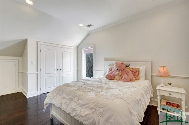 bedroom featuring crown molding, dark wood-type flooring, lofted ceiling, and a closet