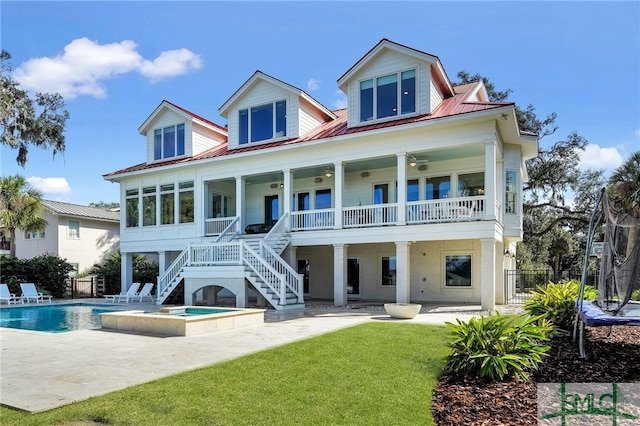 back of property with ceiling fan, a yard, a swimming pool with hot tub, and a patio area