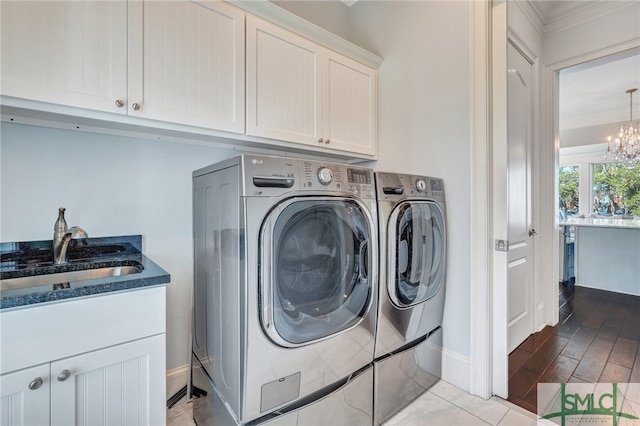 clothes washing area featuring cabinets, light hardwood / wood-style floors, washer and dryer, and a notable chandelier