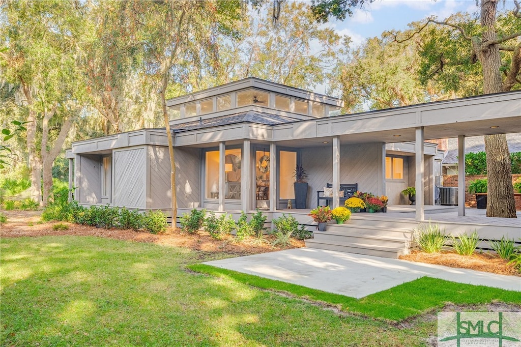 back of property featuring central AC unit, a porch, and a yard