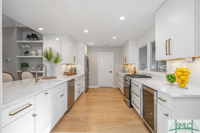 kitchen with wine cooler, appliances with stainless steel finishes, sink, light hardwood / wood-style floors, and white cabinets