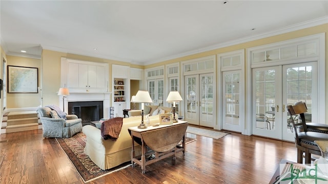 living room with hardwood / wood-style floors, french doors, built in features, and crown molding