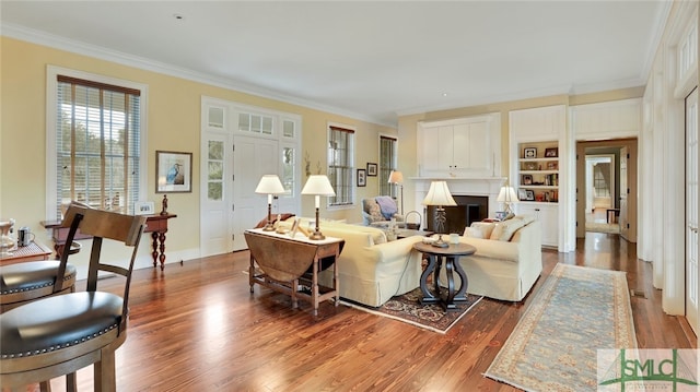 living room featuring hardwood / wood-style floors, built in features, and ornamental molding