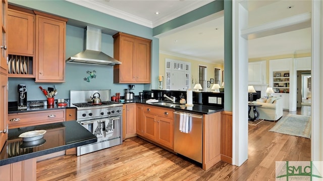 kitchen featuring sink, appliances with stainless steel finishes, ornamental molding, wall chimney exhaust hood, and light hardwood / wood-style flooring