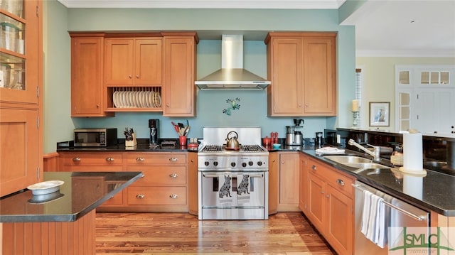 kitchen with light hardwood / wood-style flooring, wall chimney exhaust hood, ornamental molding, and stainless steel appliances