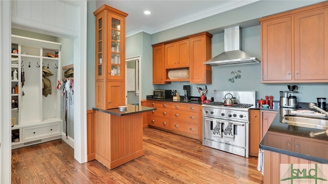 kitchen featuring crown molding, stainless steel appliances, sink, hardwood / wood-style floors, and wall chimney exhaust hood