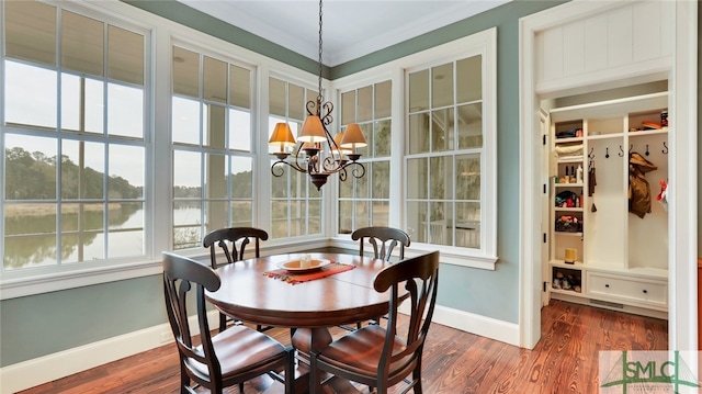 dining area featuring dark hardwood / wood-style flooring, a notable chandelier, and crown molding