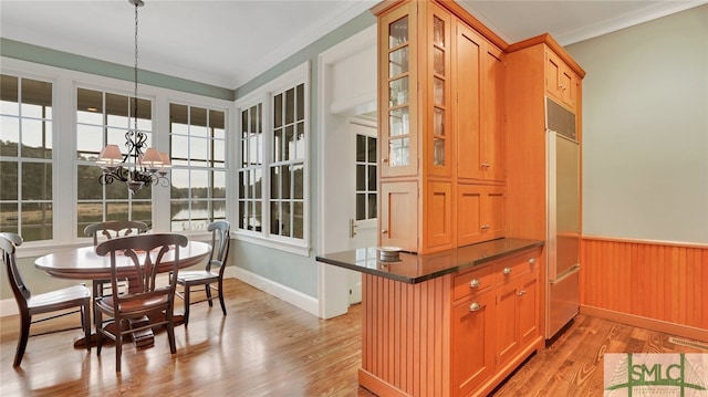 kitchen with light hardwood / wood-style floors, kitchen peninsula, an inviting chandelier, crown molding, and pendant lighting