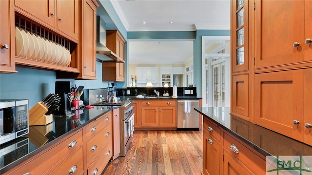 kitchen featuring light hardwood / wood-style floors, sink, crown molding, wall chimney range hood, and appliances with stainless steel finishes