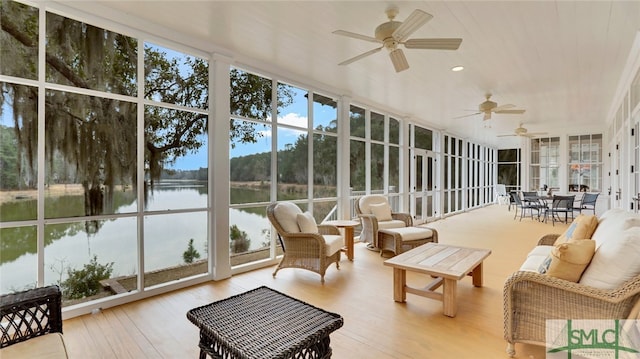 sunroom featuring ceiling fan and a water view