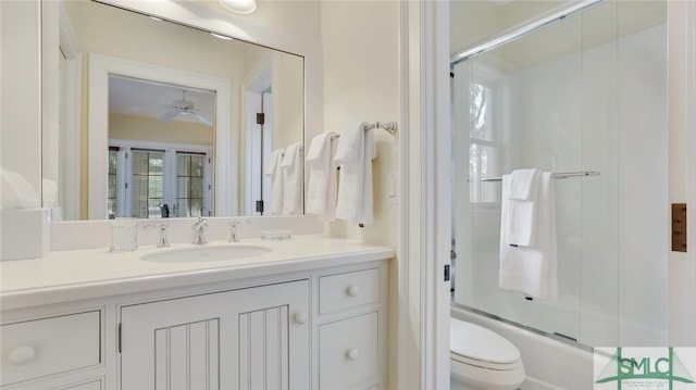 full bathroom featuring toilet, vanity, bath / shower combo with glass door, and ceiling fan