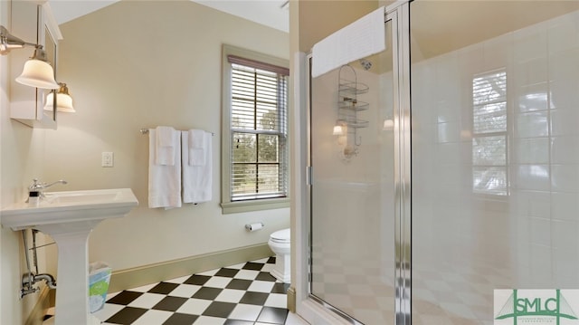 bathroom with a shower with shower door, toilet, and sink