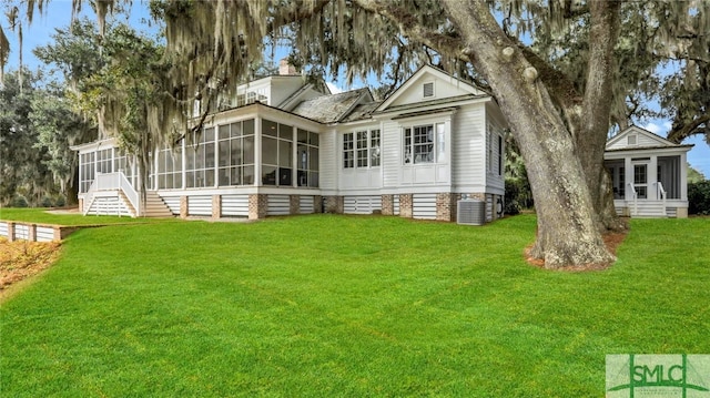 back of property featuring a lawn, a sunroom, and central AC