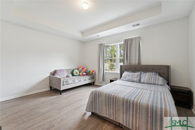 bedroom featuring hardwood / wood-style floors and a raised ceiling