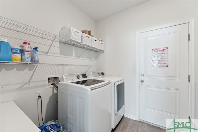 clothes washing area with washer and clothes dryer and light hardwood / wood-style flooring