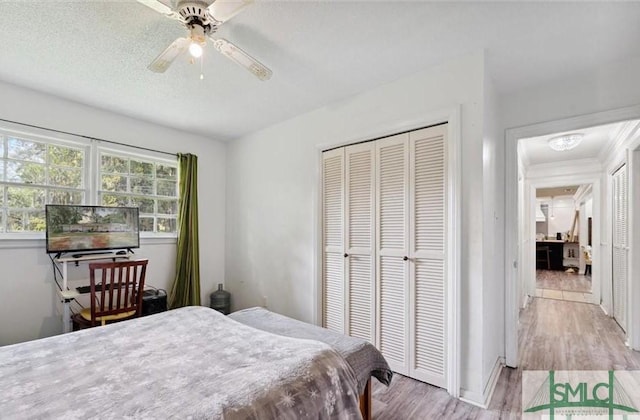 bedroom with a textured ceiling, light wood-type flooring, a closet, and ceiling fan