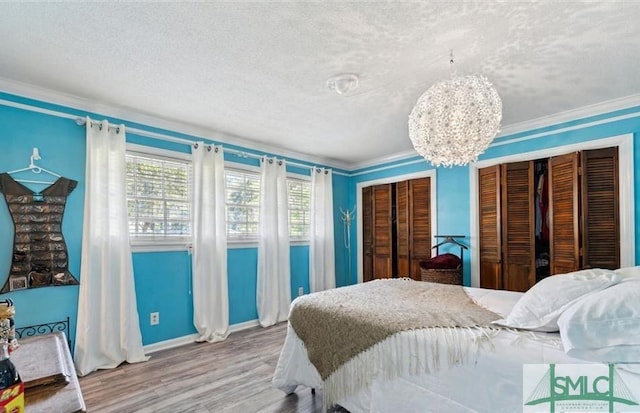 bedroom featuring a textured ceiling, hardwood / wood-style flooring, an inviting chandelier, and crown molding