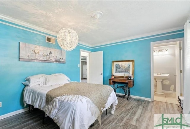 bedroom featuring ensuite bathroom, crown molding, sink, a chandelier, and hardwood / wood-style floors