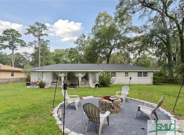 rear view of property featuring a yard, a fire pit, and a patio area